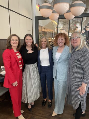 group of 5 people dressed up posing for photo inside restaurant