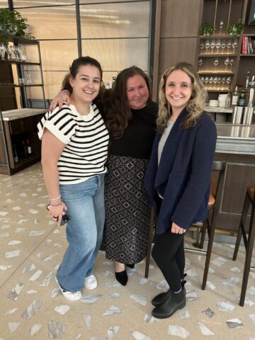 three people standing with their arms around each other for a photo